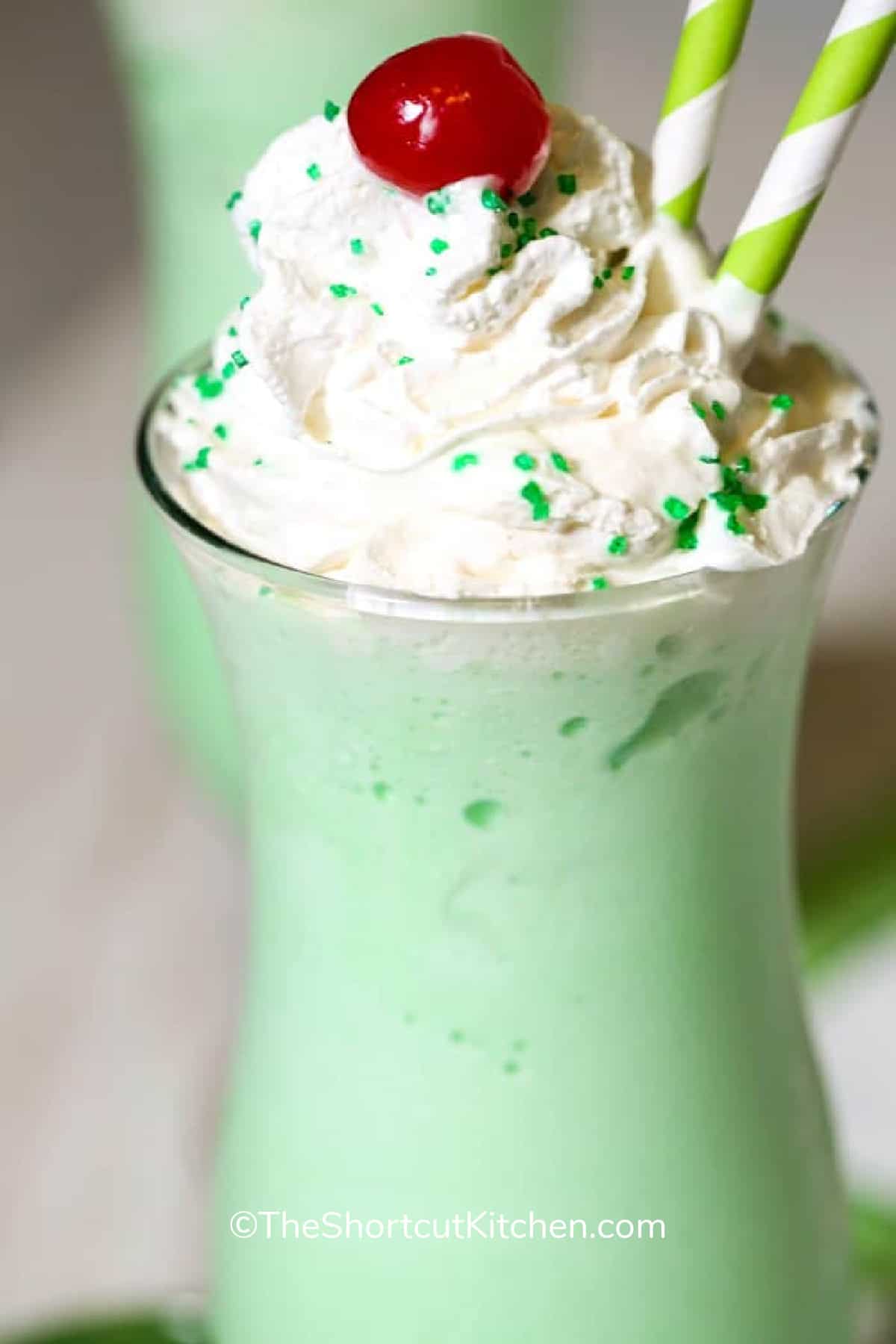 close up of copycat shamrock shake recipe topped with whipped cream, green sprinkles and a cherry