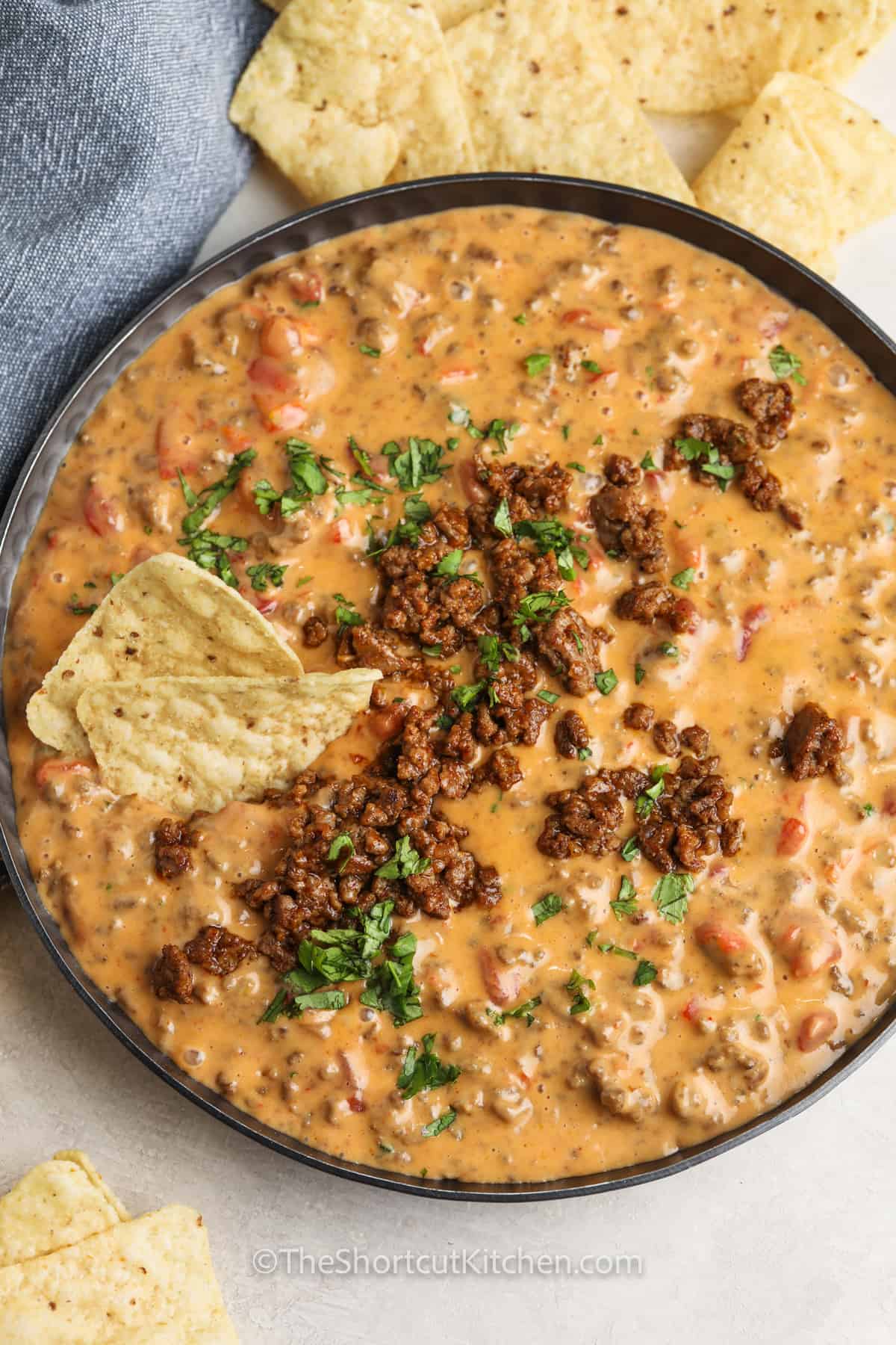 pan full of Easy Beef Queso Dip with chips around it