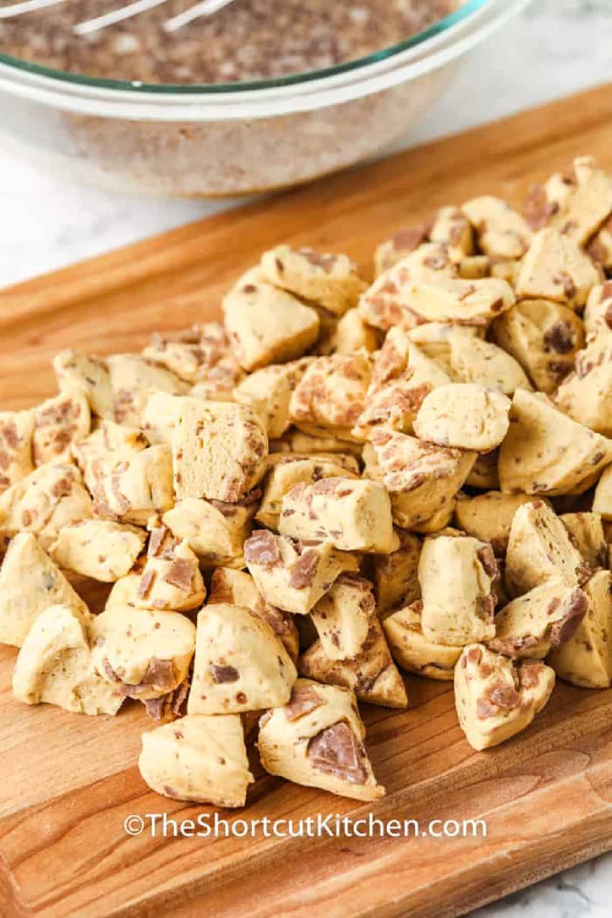 cut pieces of cinnamon roll on a cutting board to make cinnamon roll french toast casserole