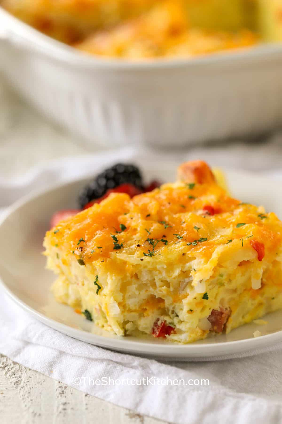 Hash Brown Breakfast Casserole on a white plate with a bite taken out of it.