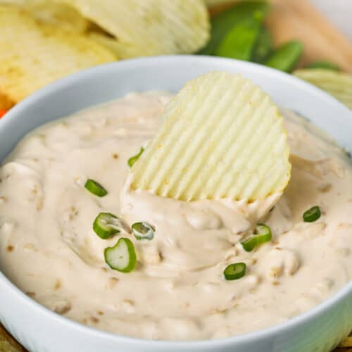 bowl of Onion Dip Recipe with a chip dipped in