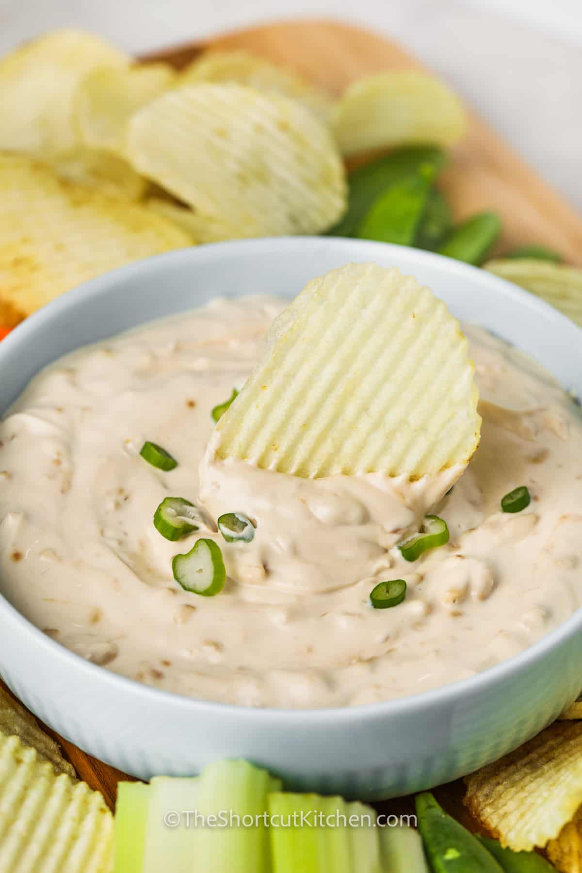 bowl of Onion Dip Recipe with a chip dipped in