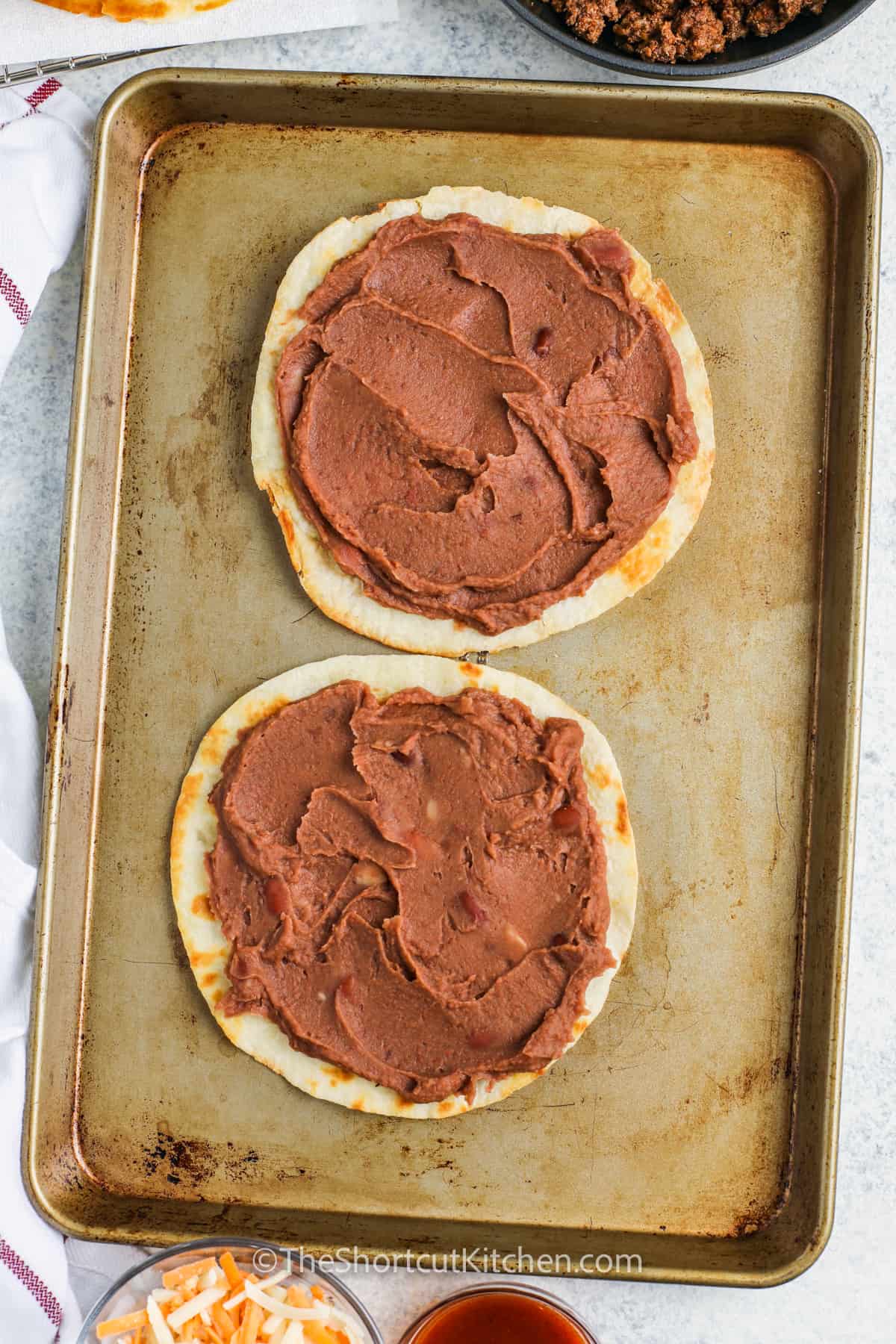adding refried beans to tortilla to make Copycat Taco Bell Mexican Pizza