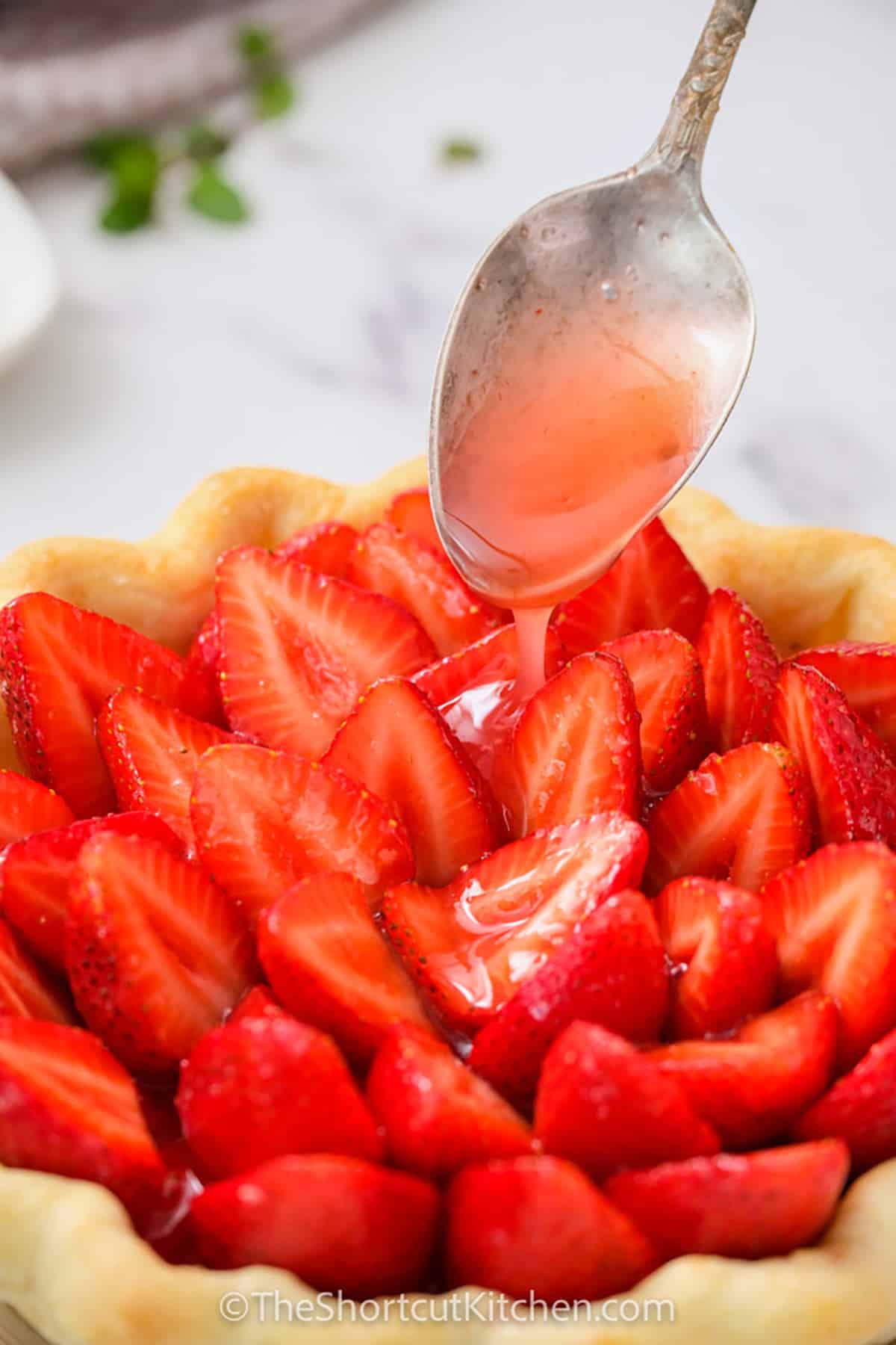 adding strawberry sauce to strawberries to make Fresh Strawberry Pie