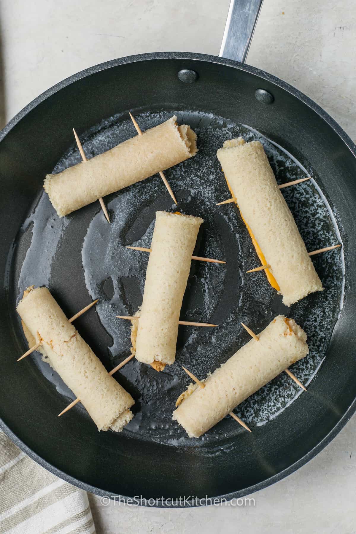 Grilled Cheese Roll Ups in a pan with butter