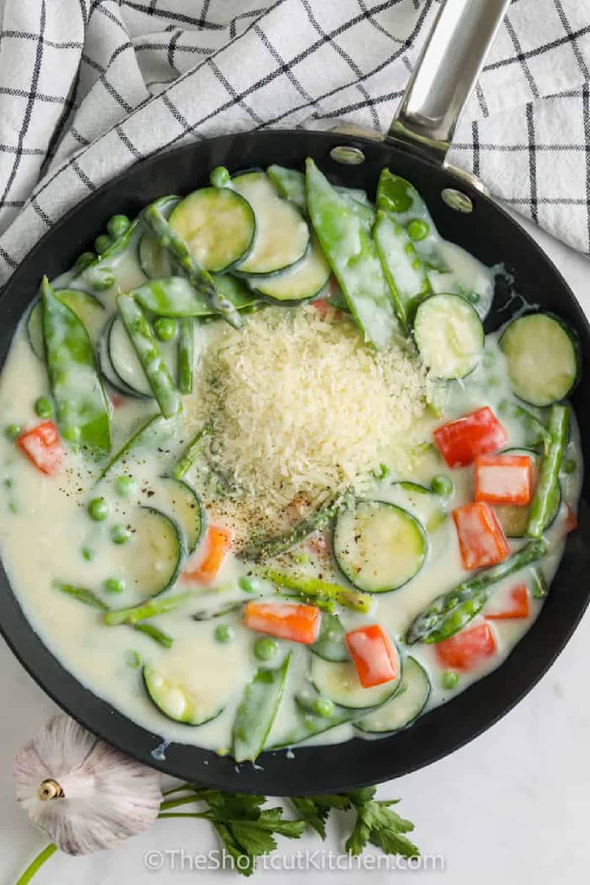 pasta primavera recipe vegetables with a creamy sauce in a frying pan.