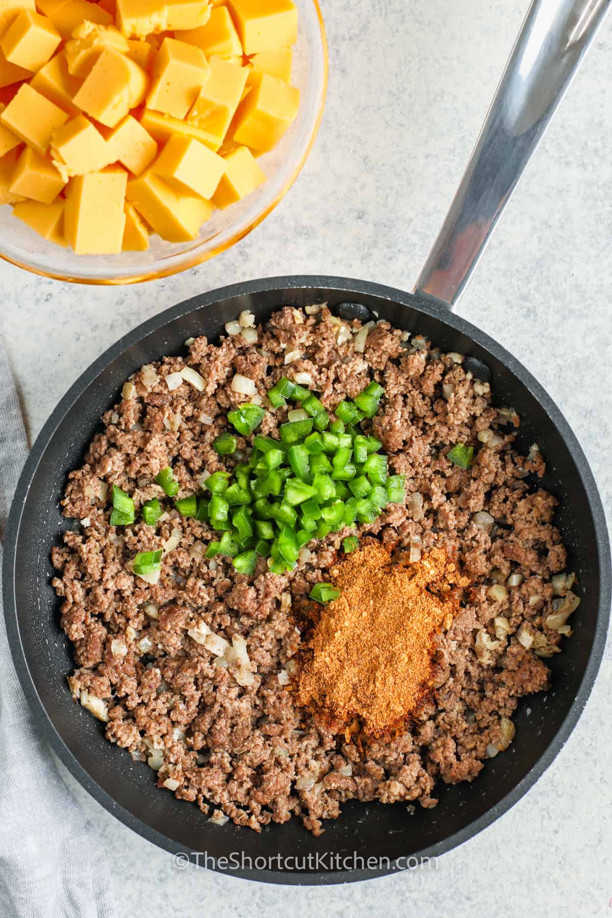 adding seasonings and peppers to beef to make Crockpot Taco Dip