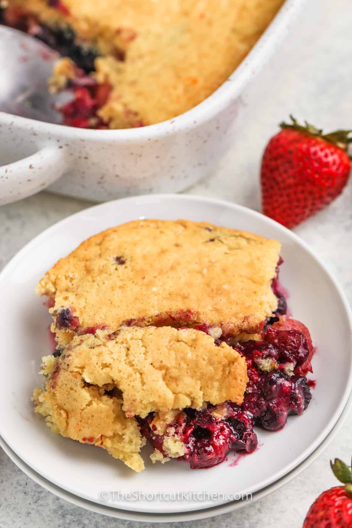 piece of Mixed Berry Dump Cake on a plate with dish full in the back