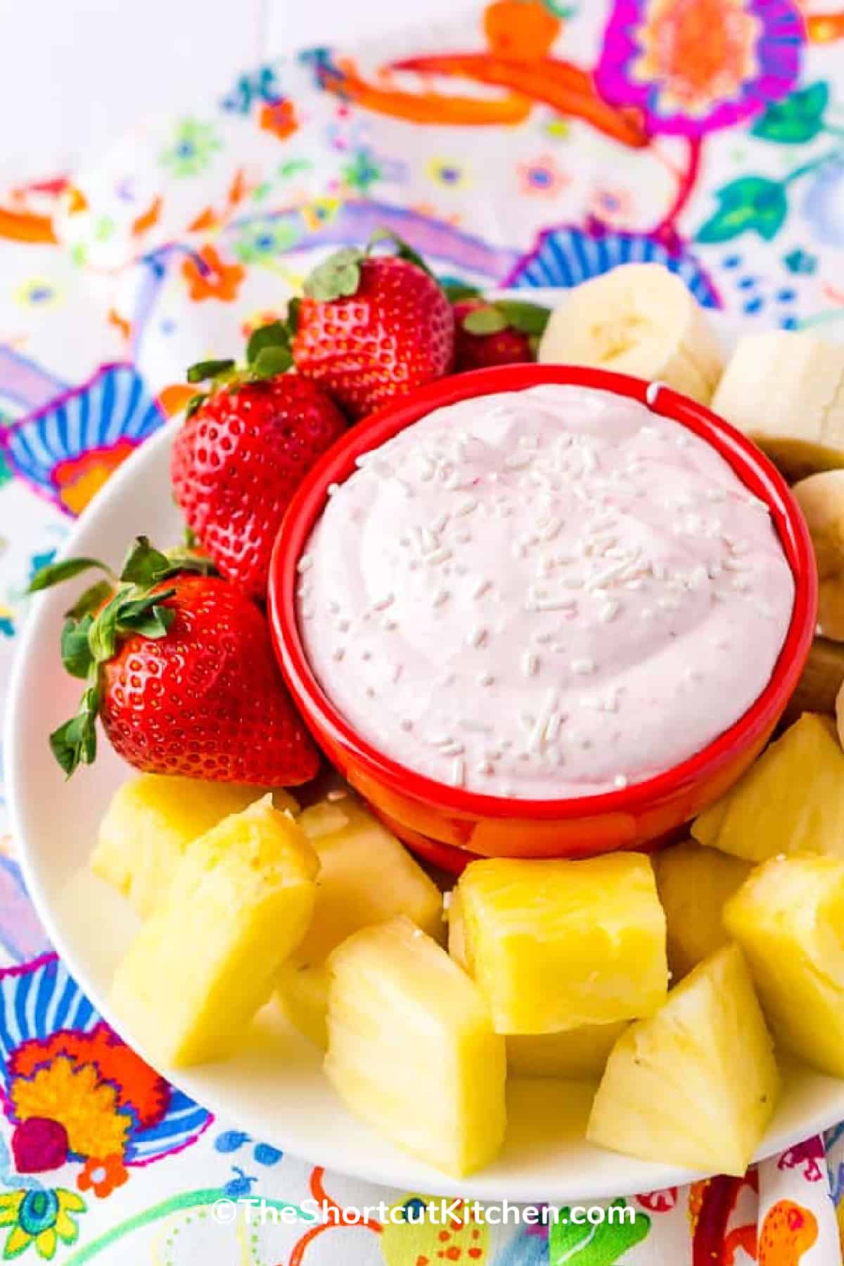 strawberry cream cheese fruit dip in a bowl with strawberries, pineapples and bananas on the side