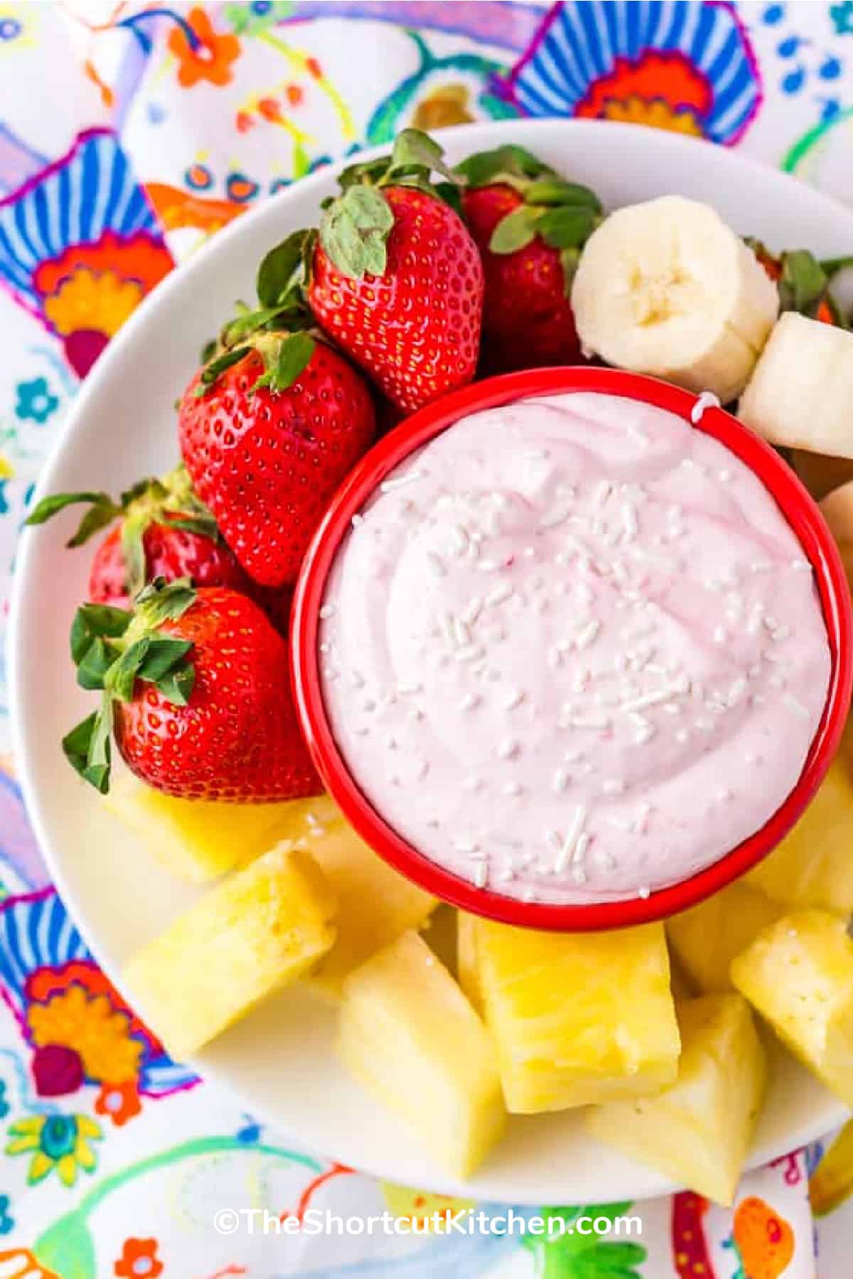 strawberry cream cheese fruit dip in a bowl with fruit on the side of a white plate