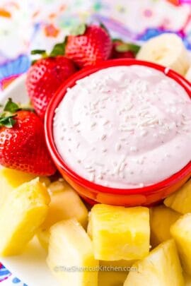 close up of strawberry cream cheese fruit dip in a bowl with fruit on the side