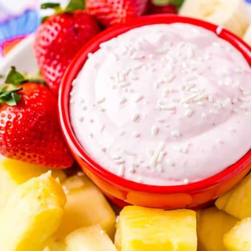 close up of strawberry cream cheese fruit dip in a bowl with fruit on the side