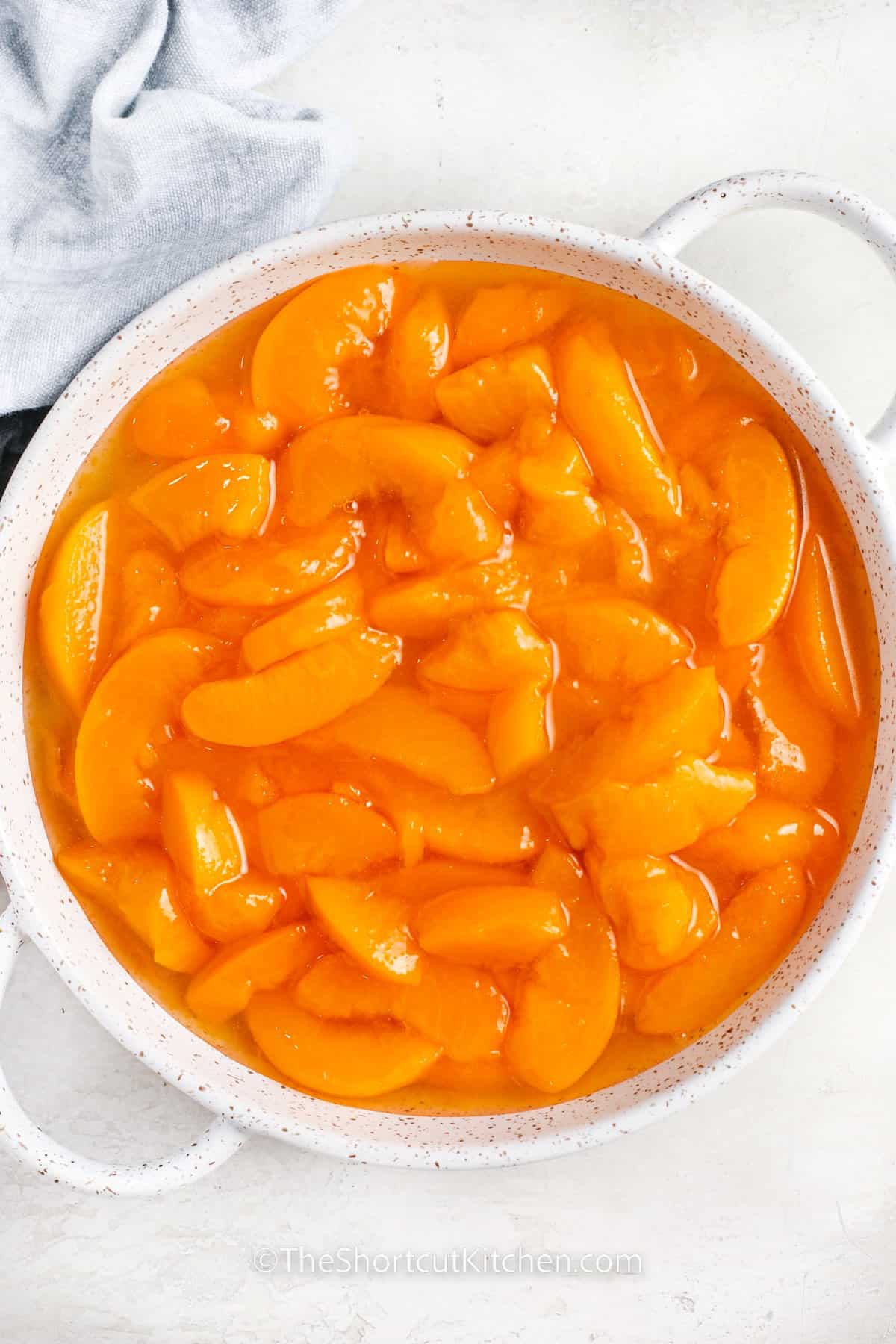 adding peaches to dish to make Bisquick Peach Cobbler Recipe