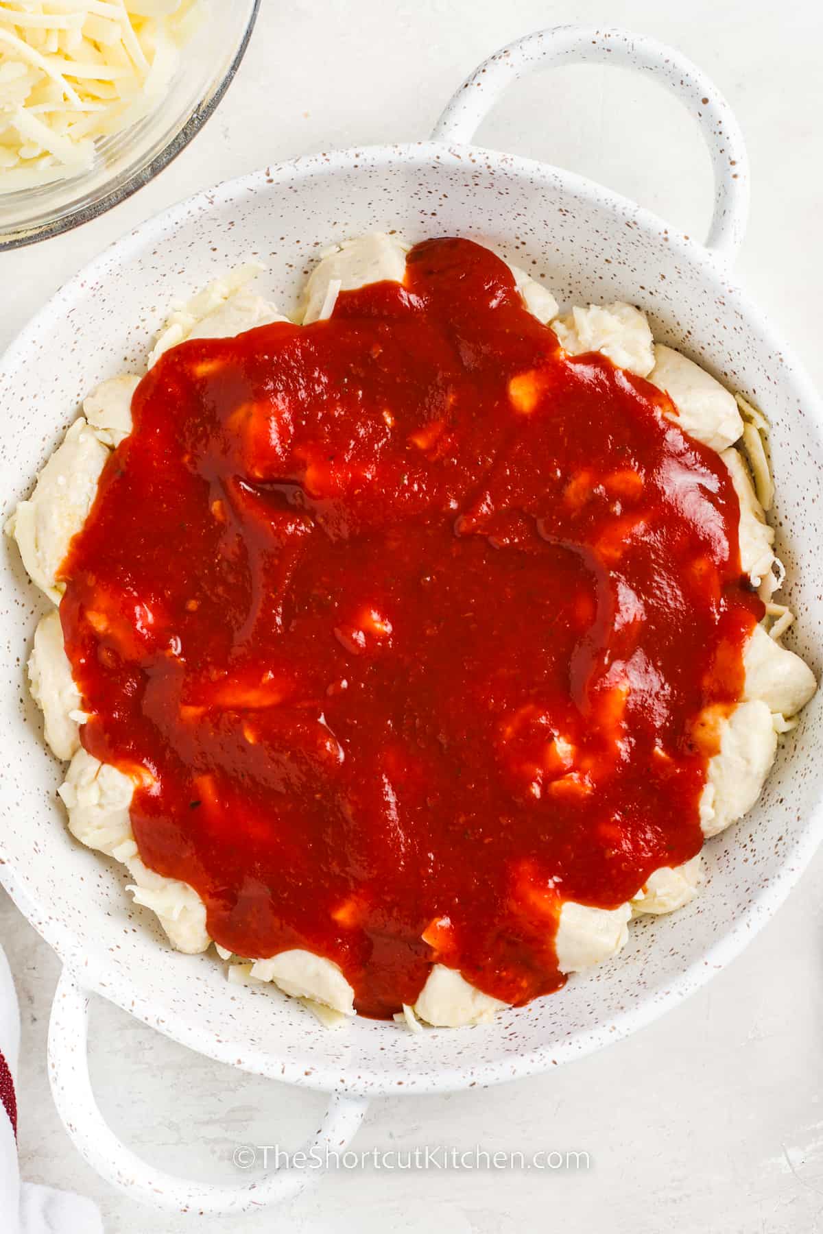 adding pizza sauce to biscuits to make Cheesy Bubble Pizza Recipe