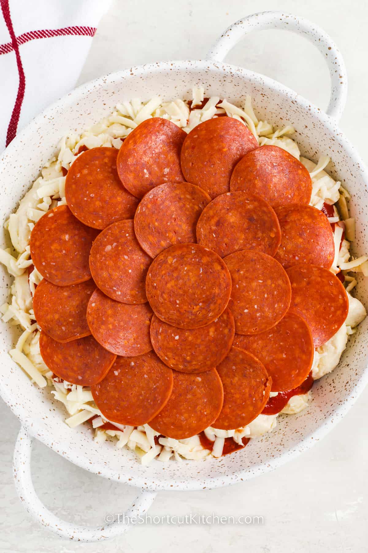 adding pepperoni and more cheese to dish to make Cheesy Bubble Pizza Recipe