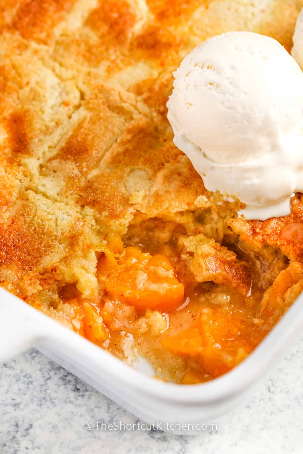 Peach Dump Cake in a dish with ice cream