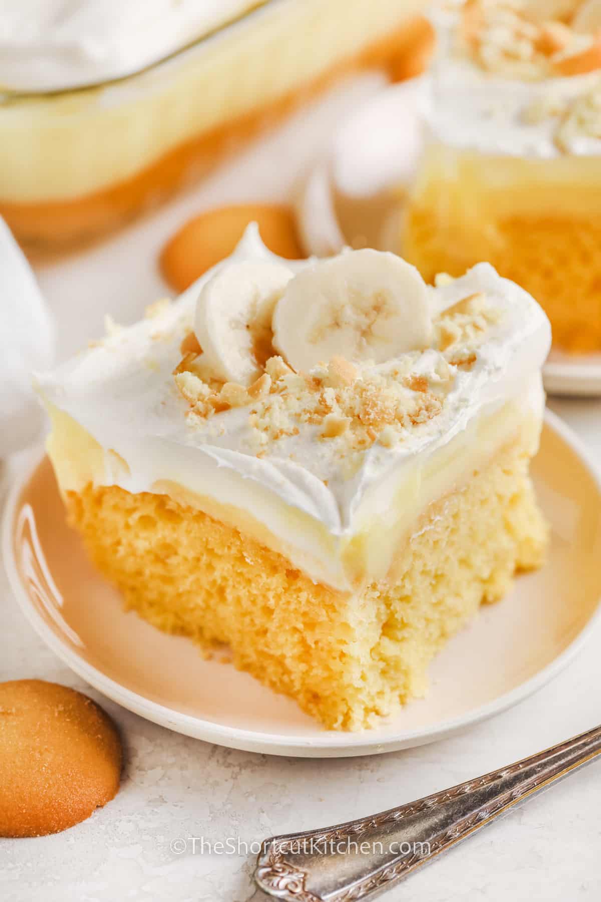 A slice of banana pudding poke cake being served on a plate.