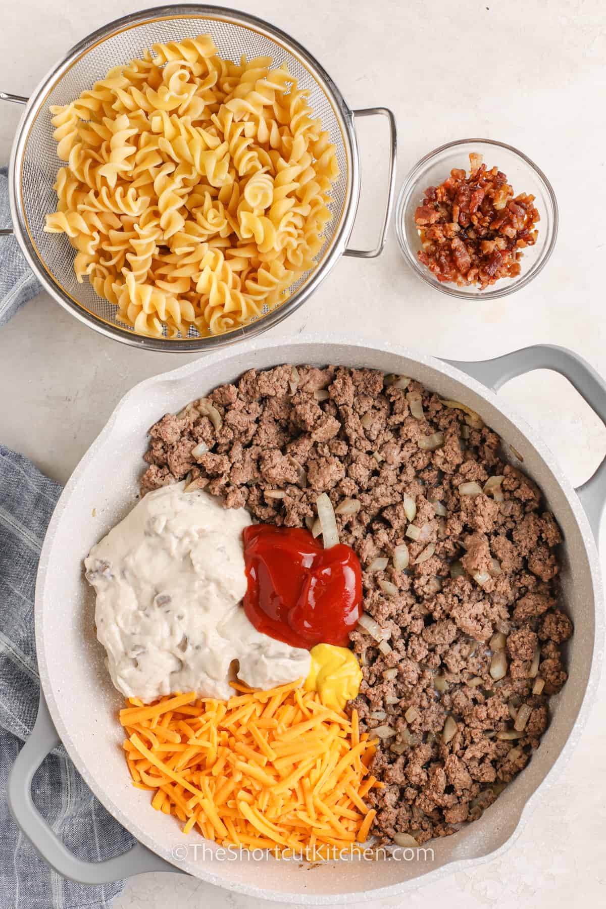 Pasta and bacon bits in separate bowls with all other ingredients combined in a pot.