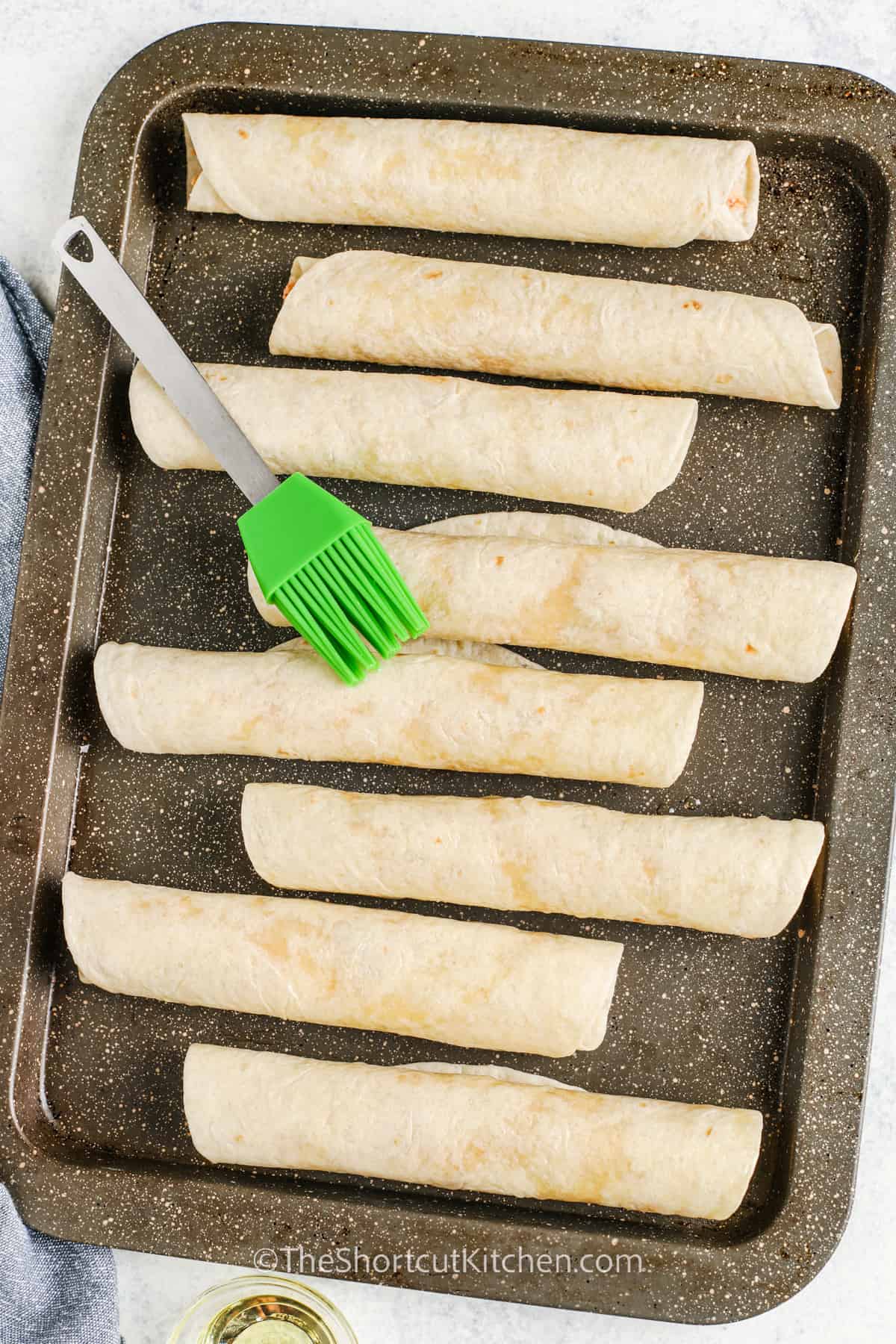 brushing butter over Chicken Taquitos before cooking