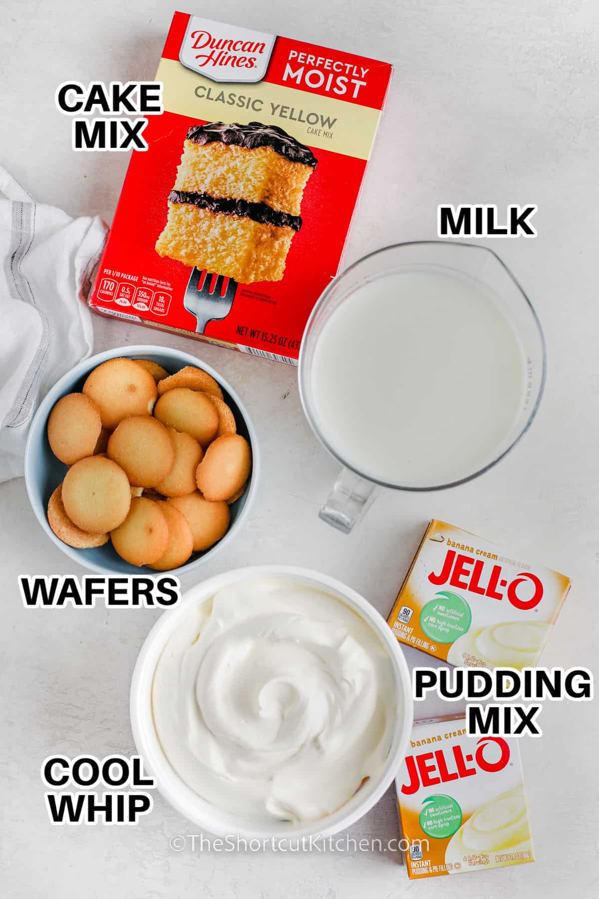 Ingredients to make a banana pudding poke cake labeled: cake mix, milk, wafers, cool whip, pudding mix.