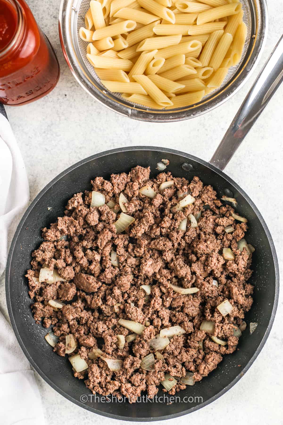 browned ground beef and onions in a skillet, and pasta and spaghetti sauce on the side, to make pizza pasta bake