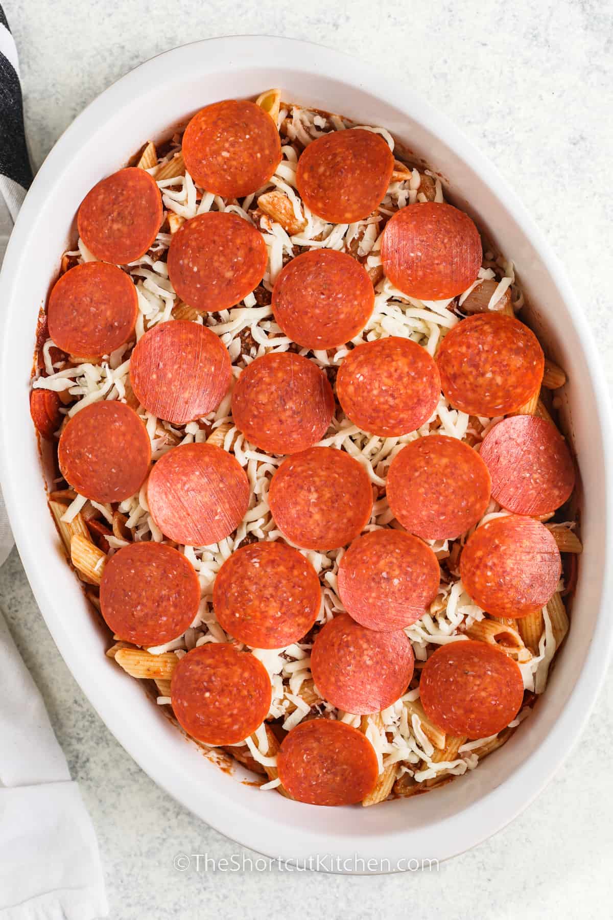 Pizza pasta bake assembled in a casserole dish