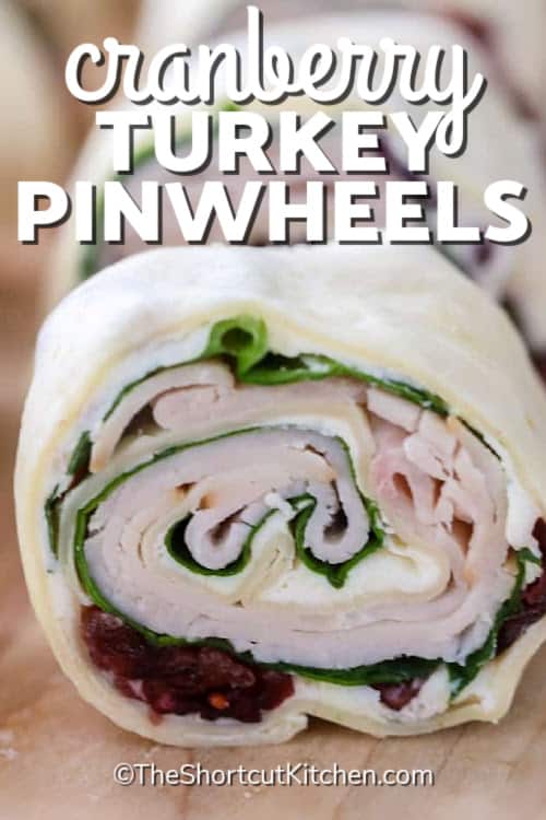 cranberry turkey pinwheels on a wooden board, with a title