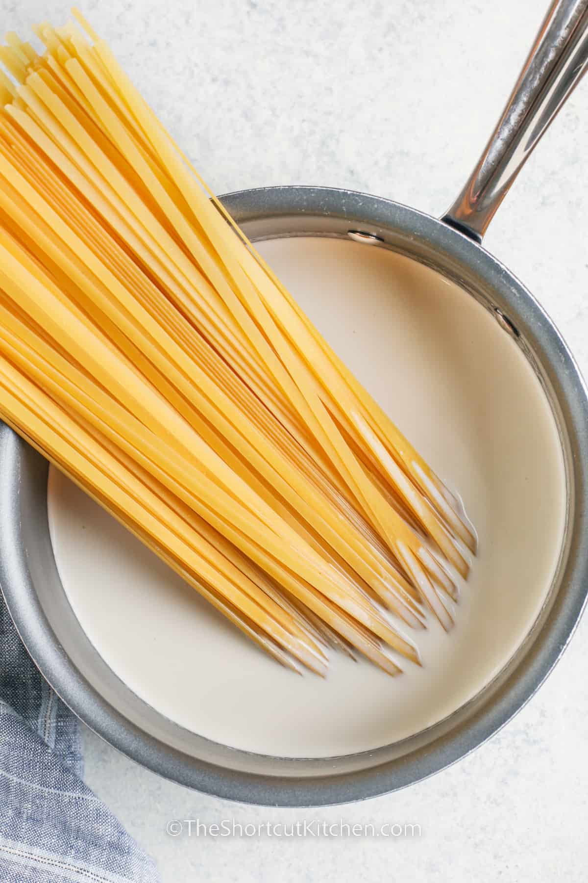 fettuccine noodles in a pot of creamy sauce