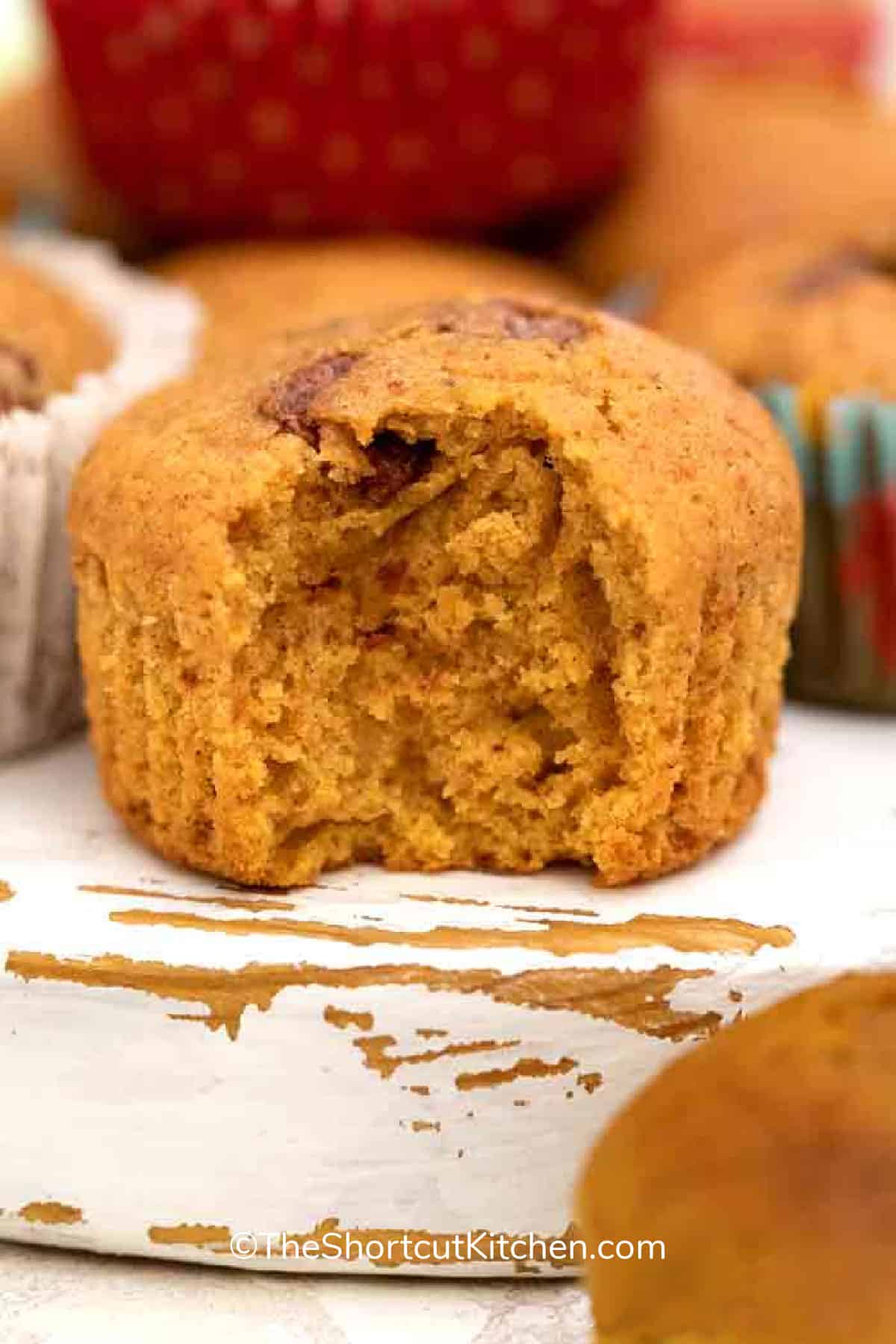 a pumpkin chocolate chip muffin sitting on a wooden board
