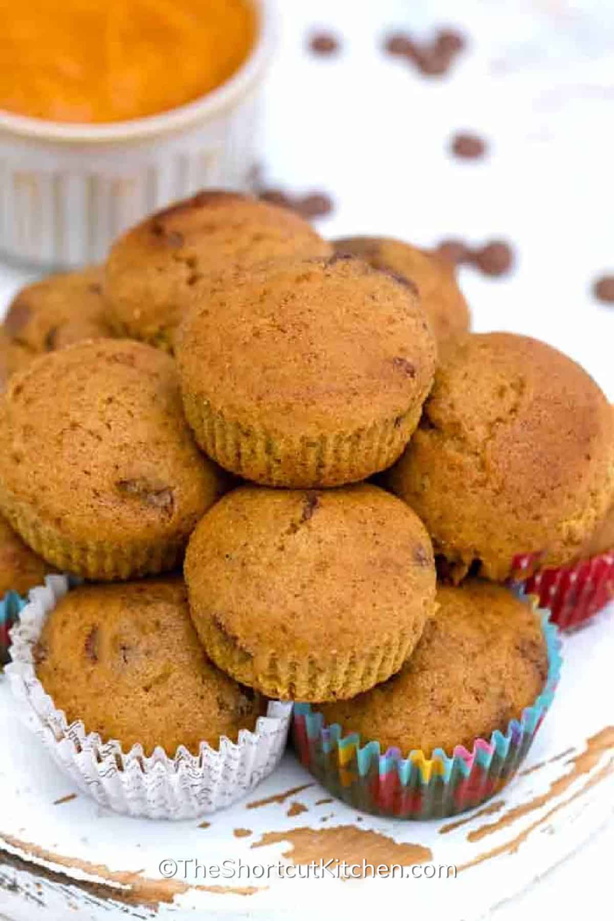 pumpkin chocolate chip muffins piled together on a wooden board
