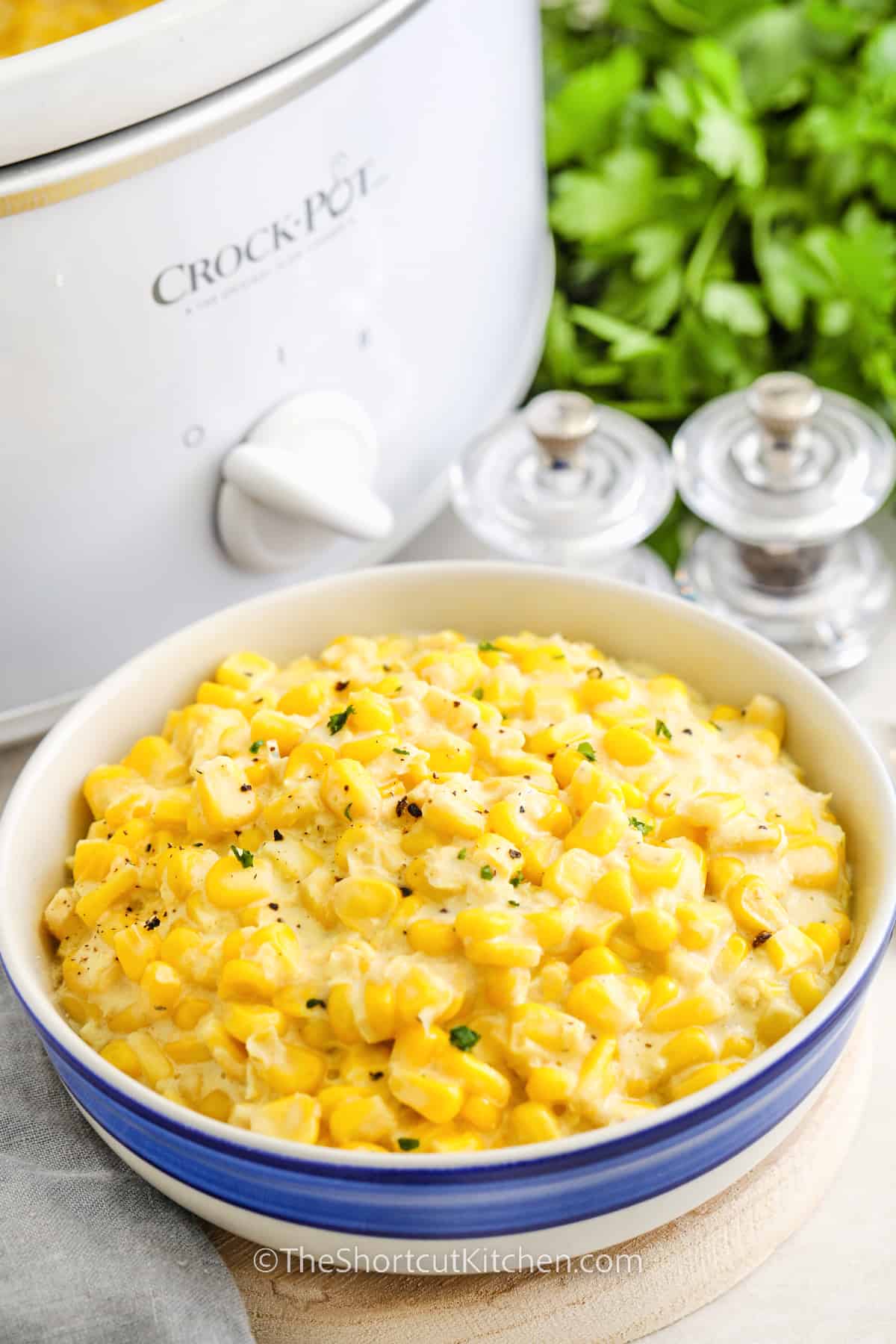 a bowl of creamed corn in front of a crockpot