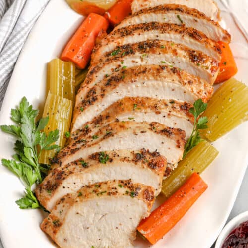 sliced crockpot turkey breast on a white serving platter
