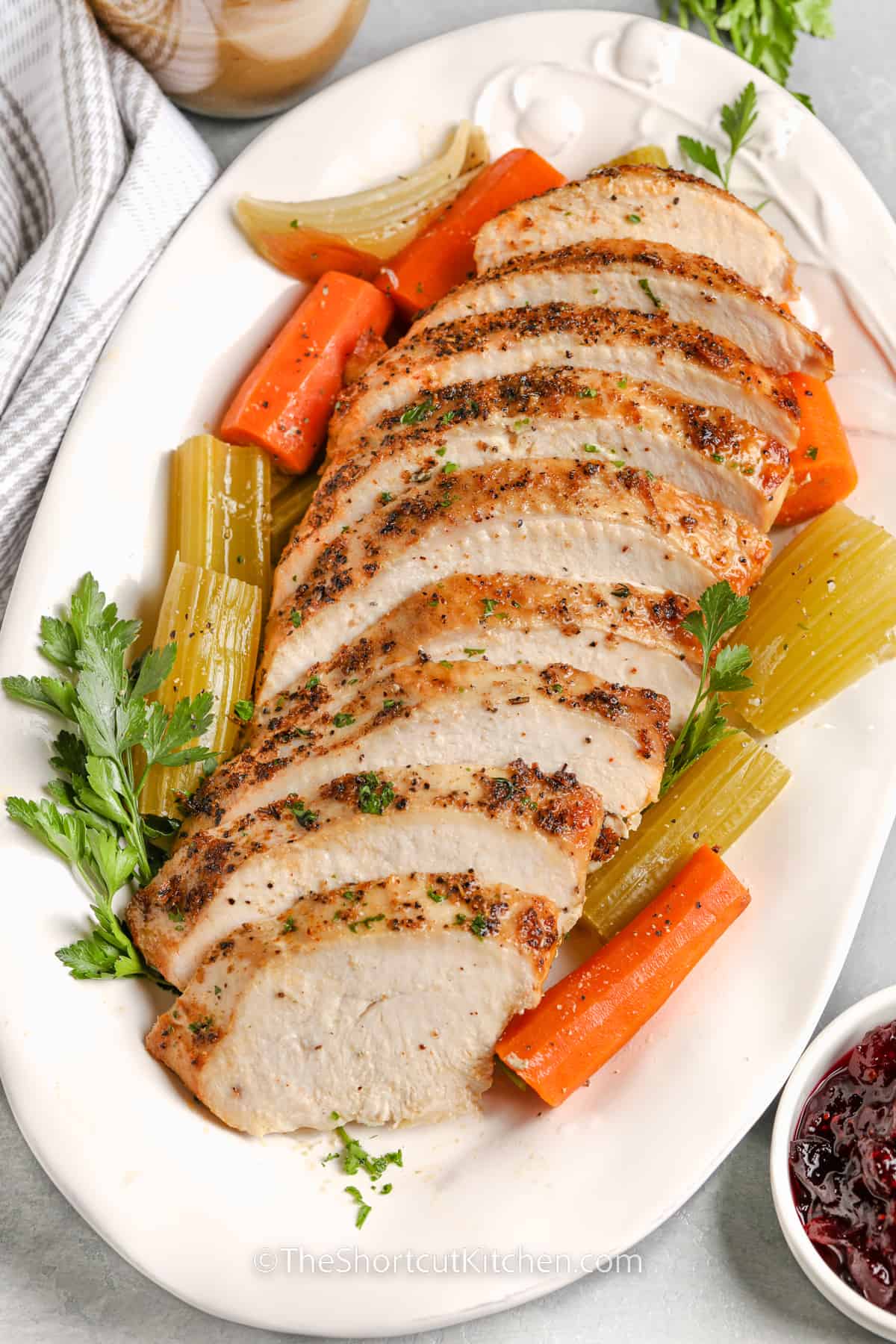 sliced crockpot turkey breast on a white serving platter