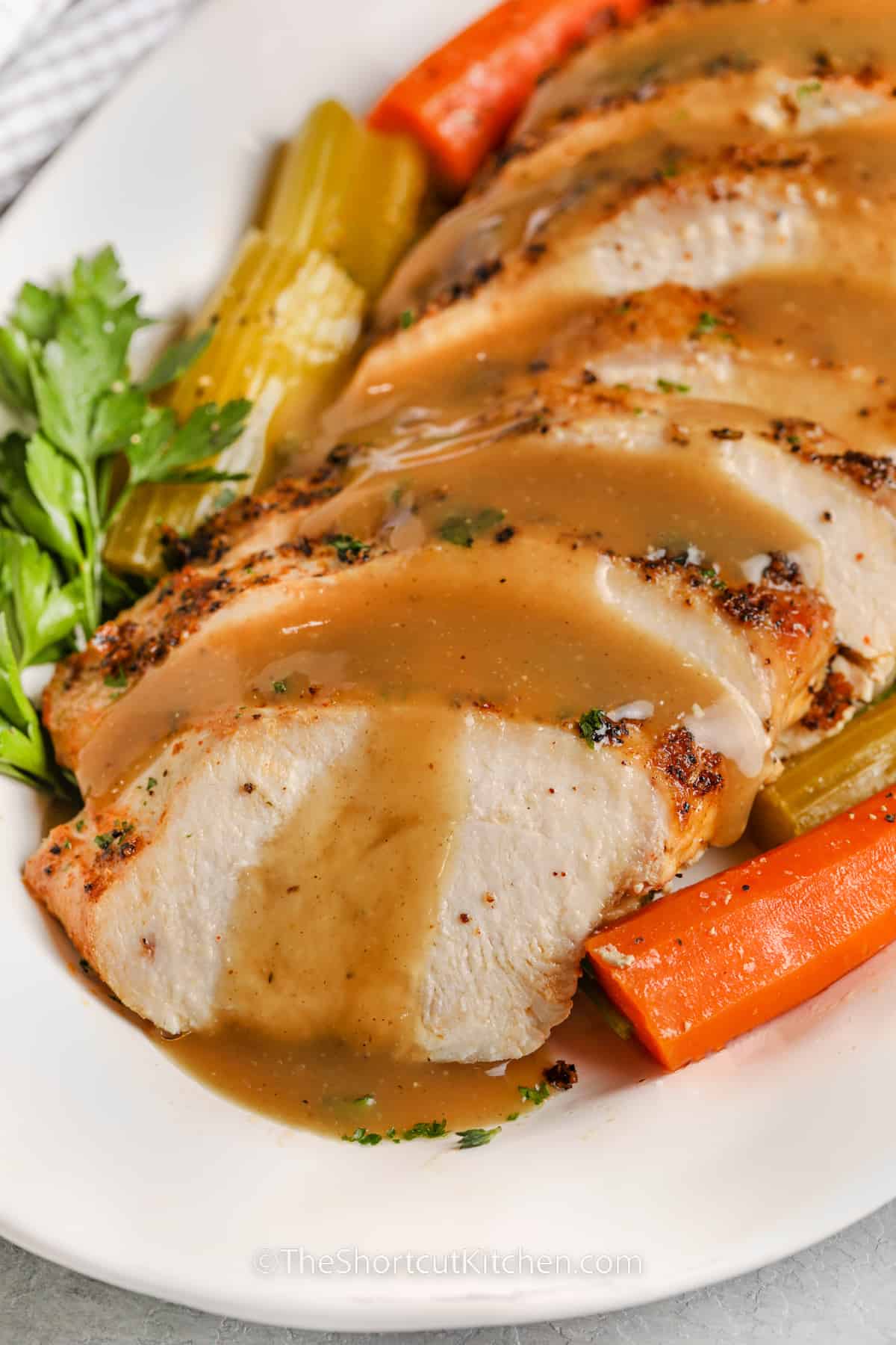 sliced crockpot turkey breast with gravy and garnish