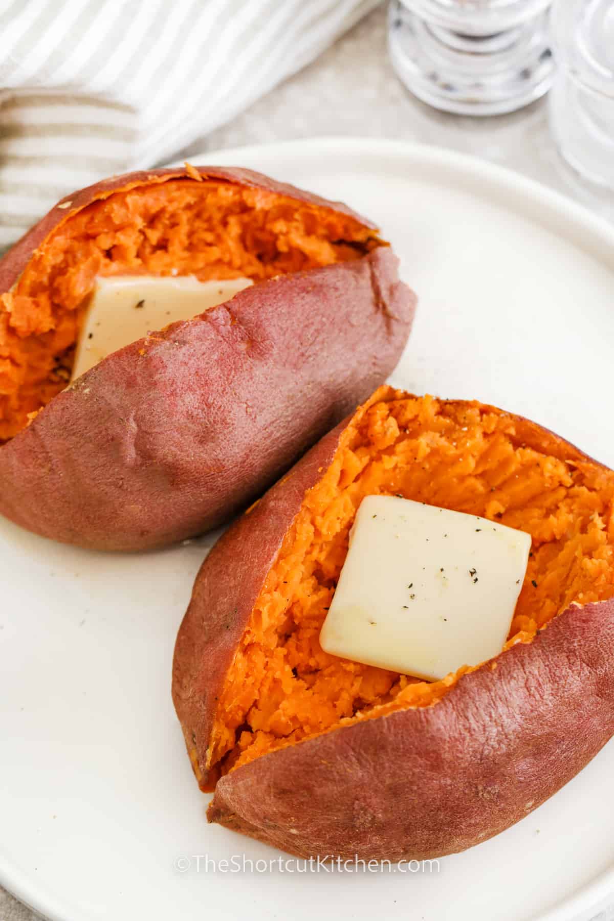 sweet potatoes on a plate cut open with pats of butter