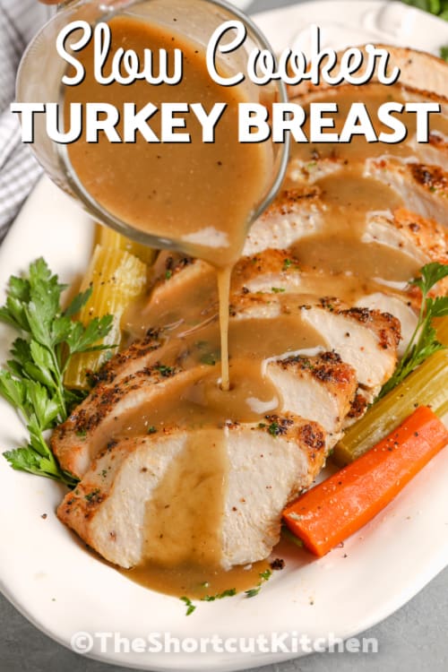 slices of crockpot turkey breast on a serving plate with gravy being poured on and writing