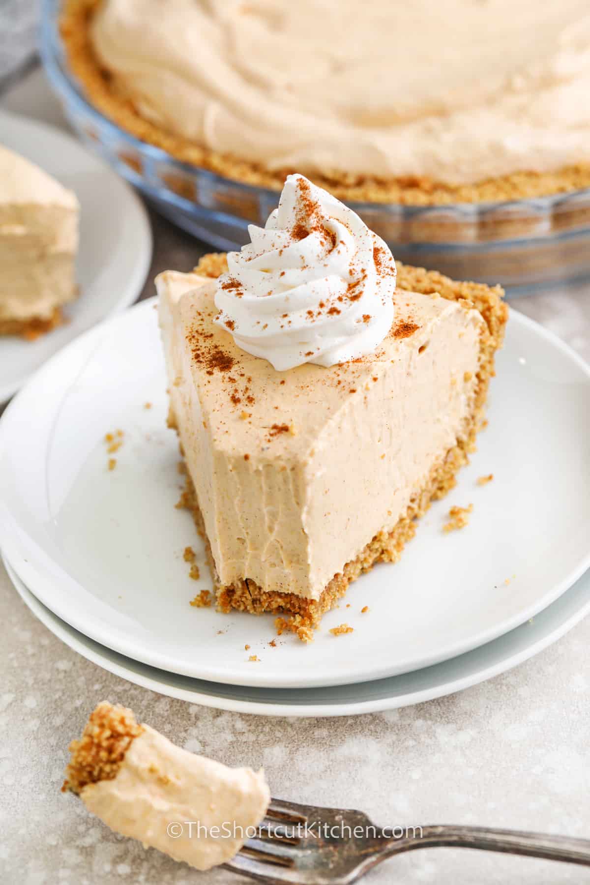 A slice of no bake pumpkin pie with whipped cream on top with a bite take out of it