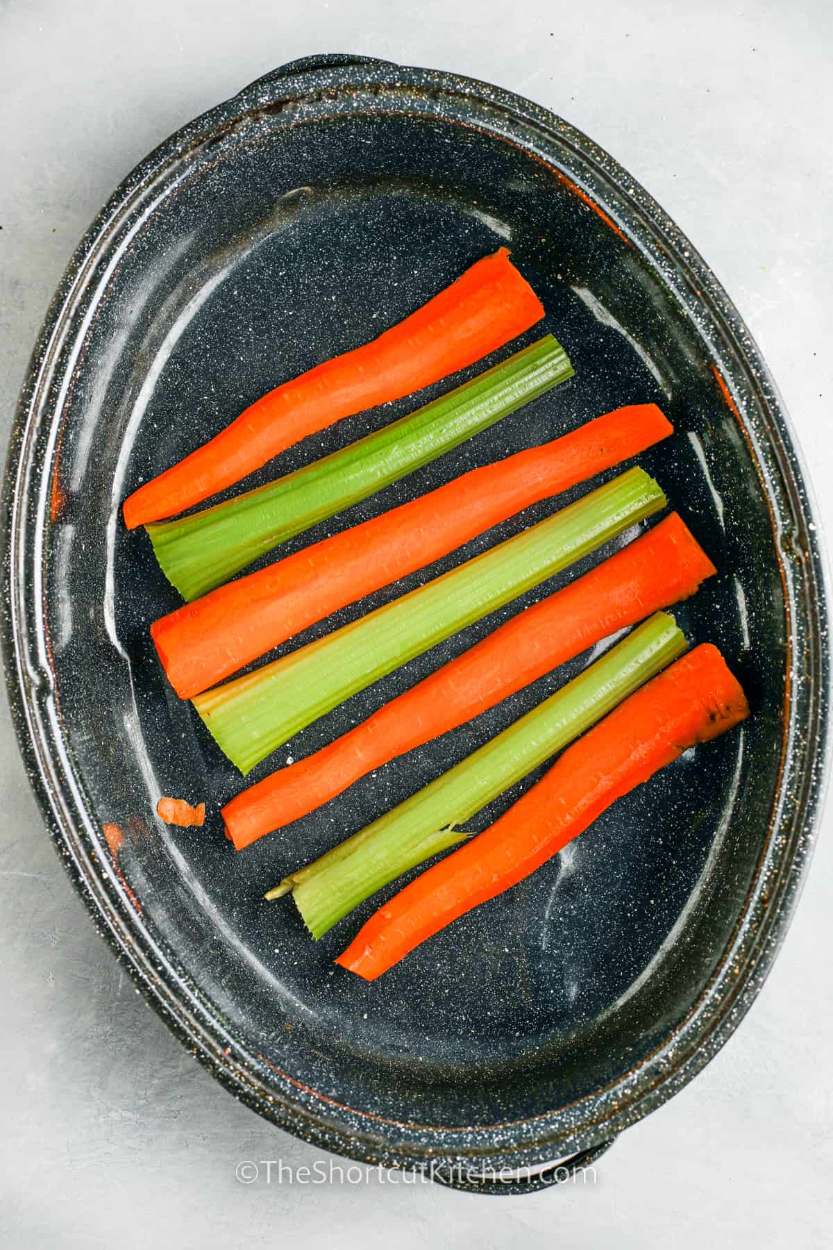 carrots and celery in the bottom of a roasting pan for Roast Turkey
