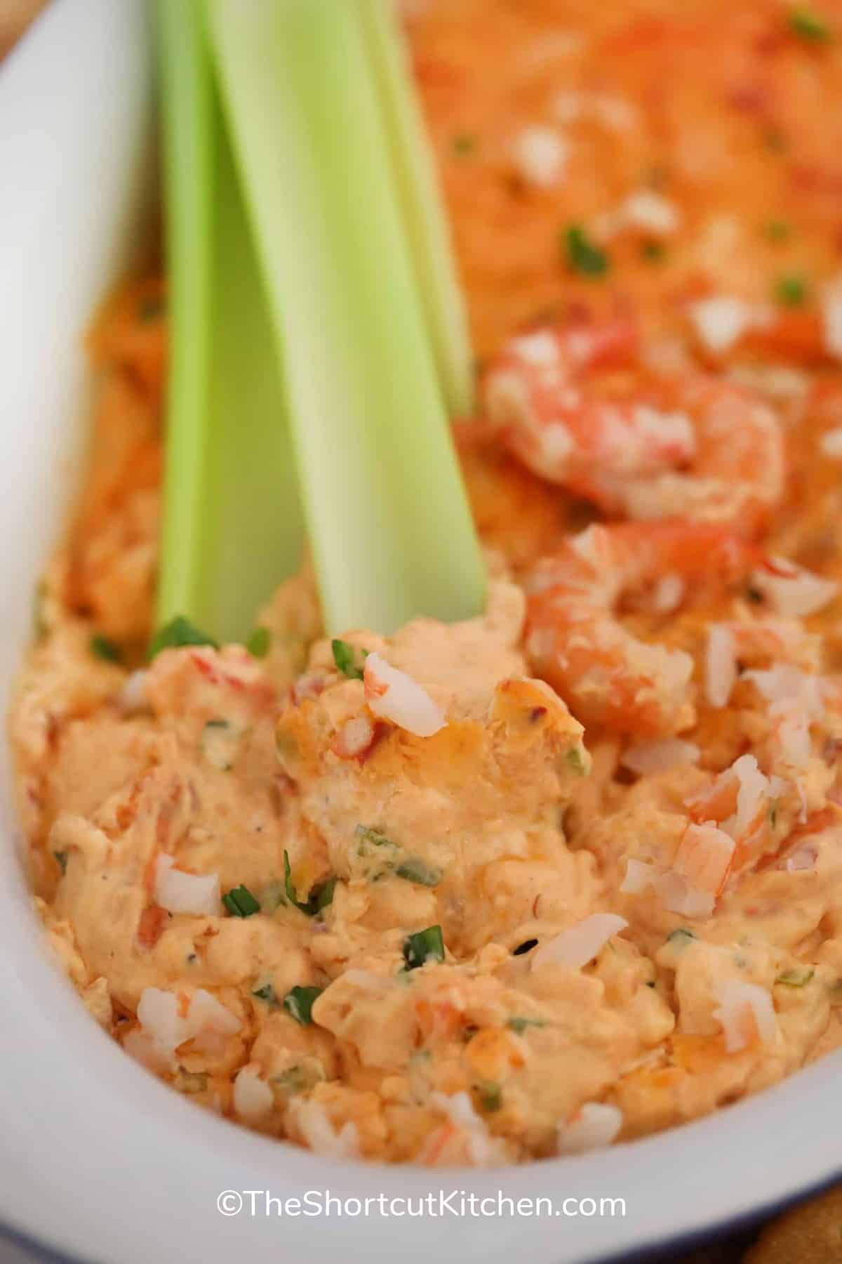 Shrimp dip in a white bowl with celery sticks and shrimp
