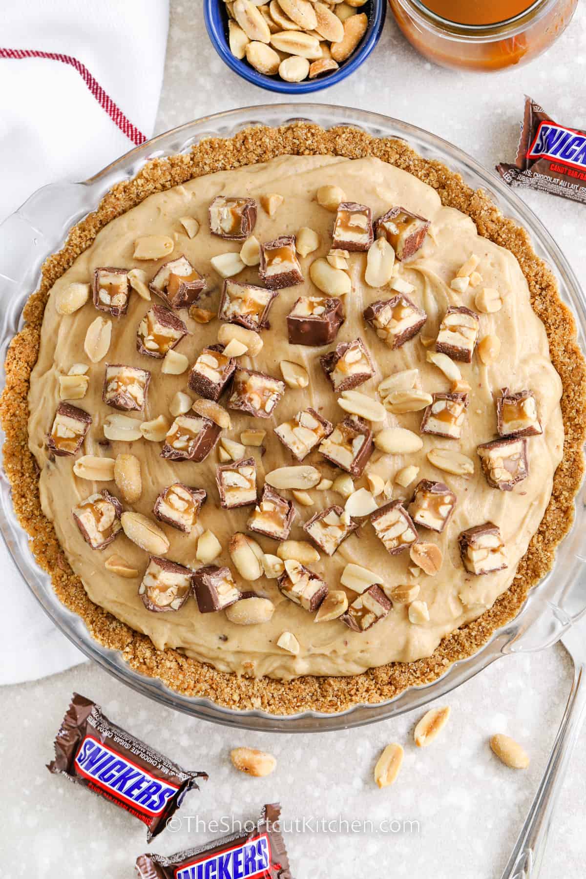 a prepared no bake snickers pie topped with snickers and peanuts
