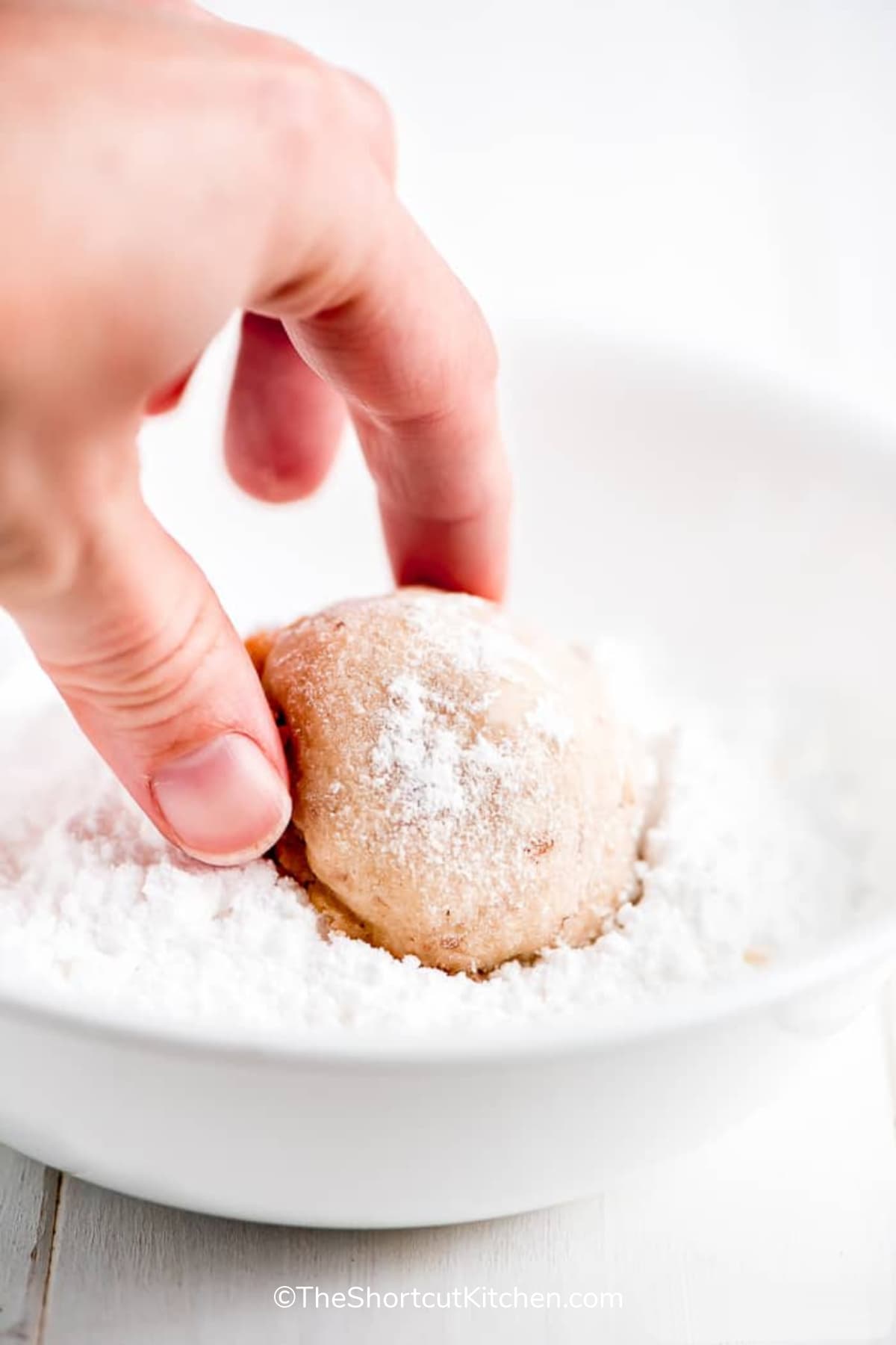 coating snowball cookies in powdered sugar