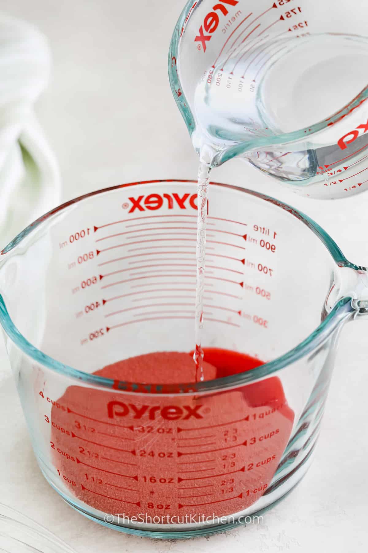 pouring water into a glass measuring cup with jello