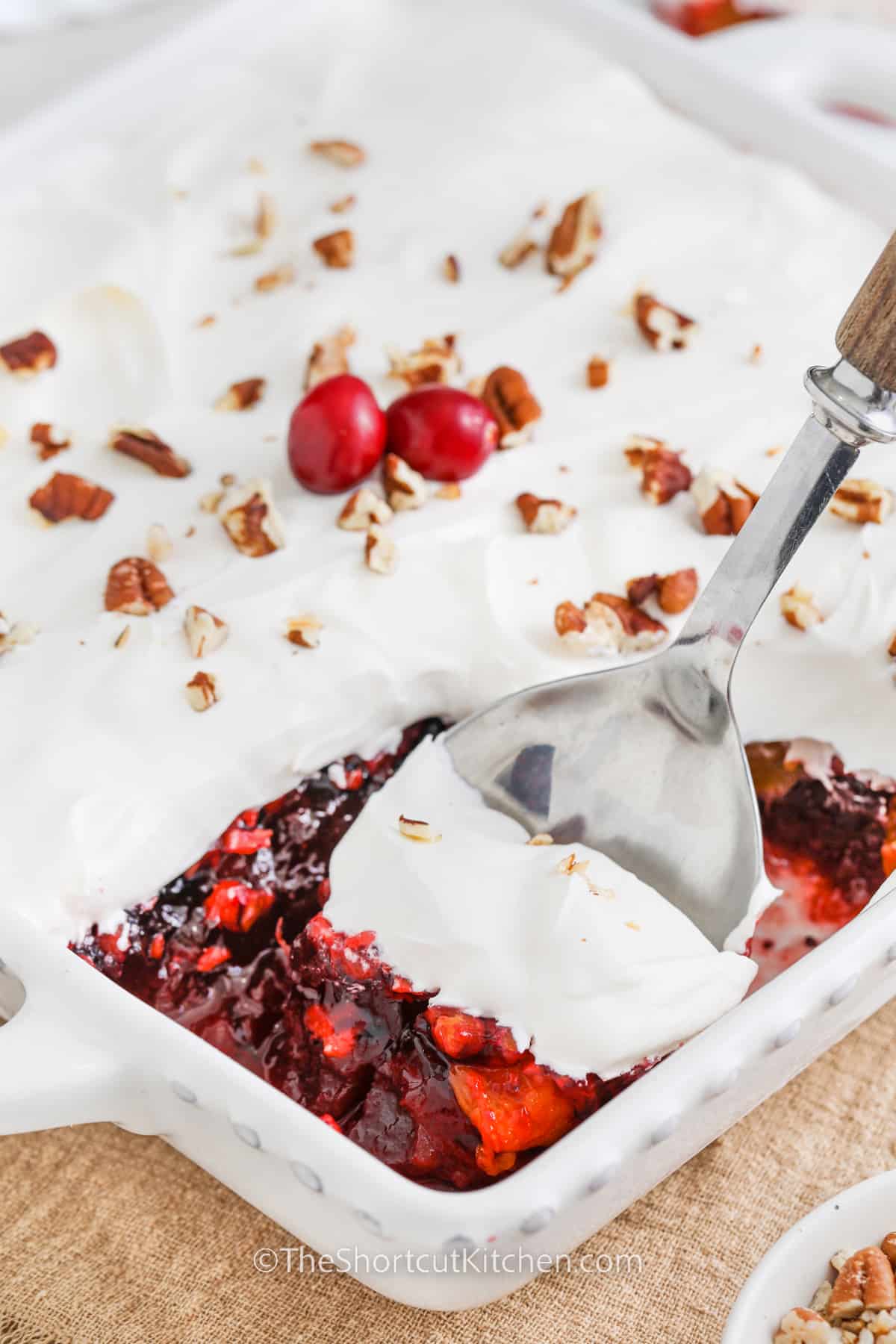 cranberry jello salad in a dish with a scoop being taken out