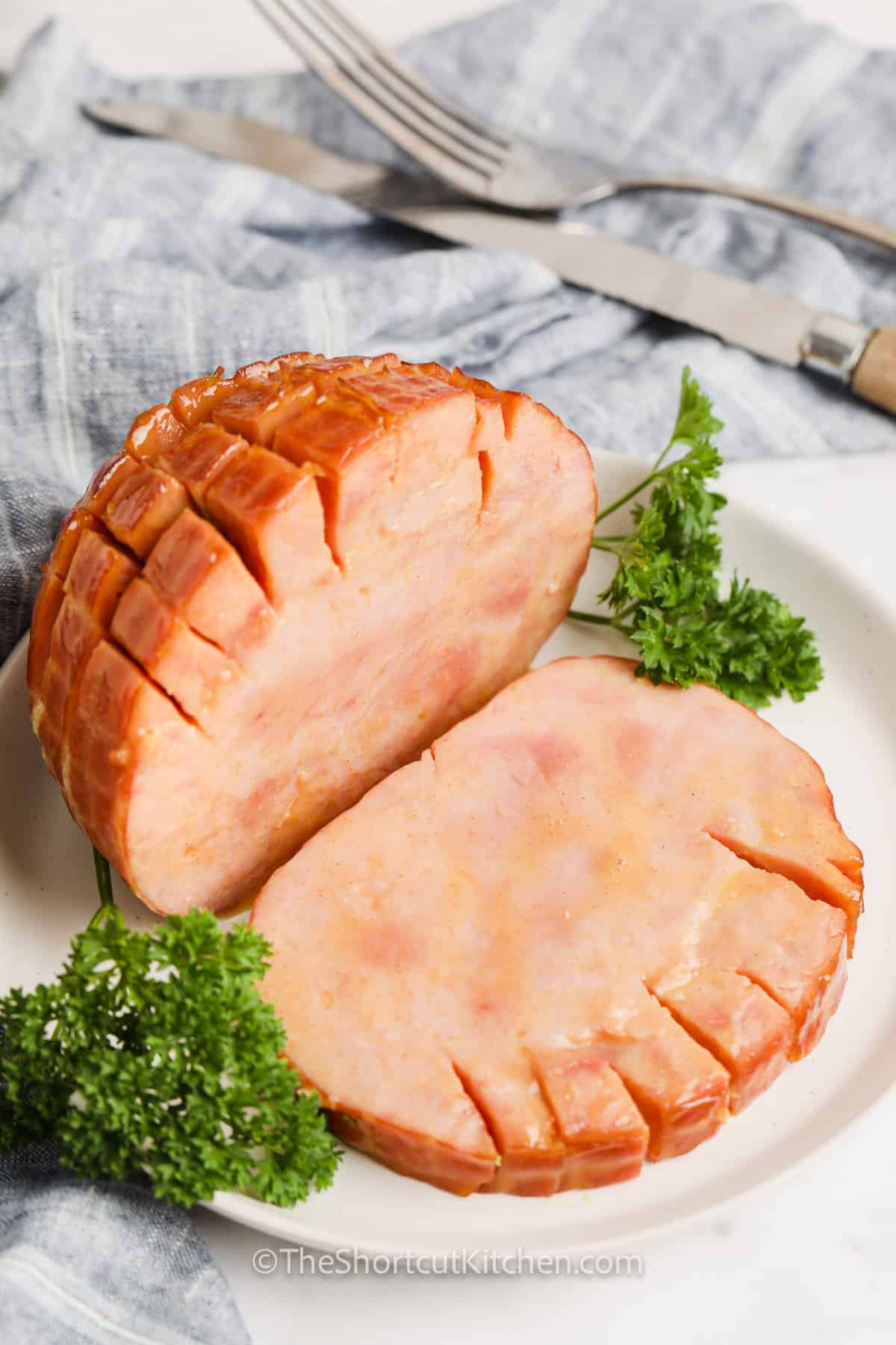 sliced Crockpot brown sugar ham on a white plate with garnish