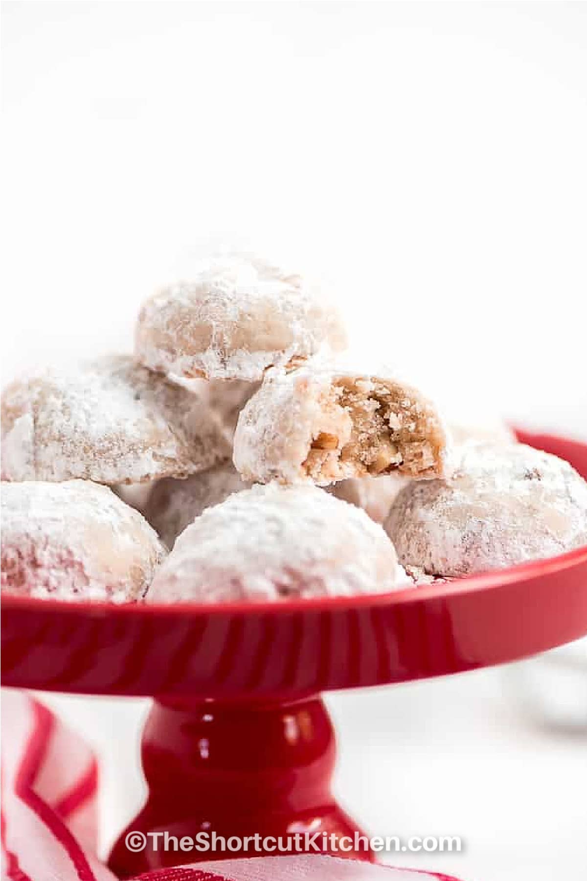 snowball cookies on a red plate with a bite taken out of one