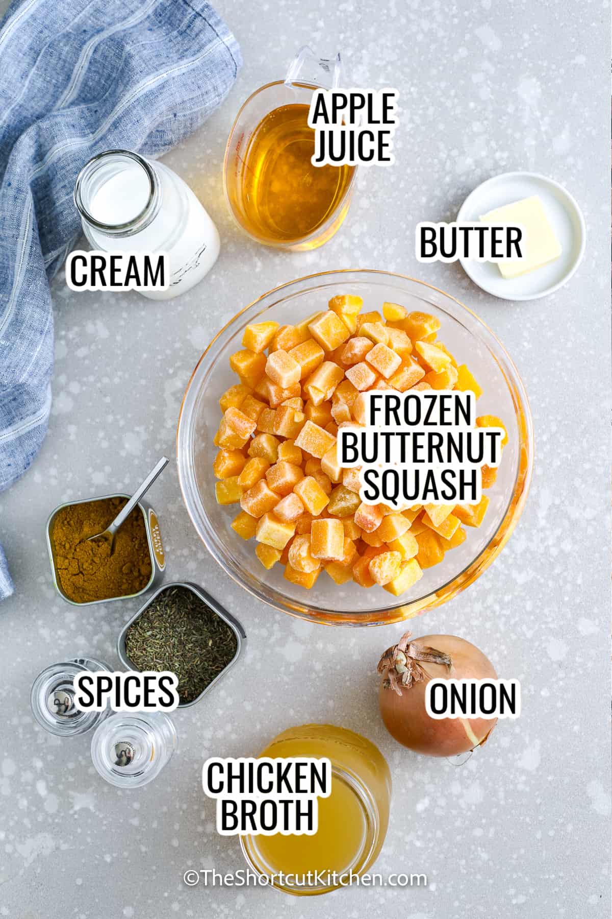 ingredients assembled to make easy butternut squash soup, including butternut squash, chicken broth, onion, cream, butter, and apple juice