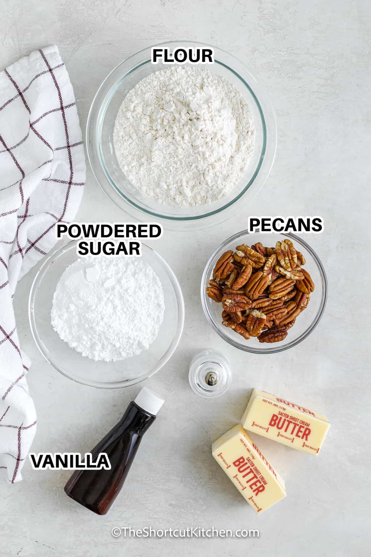 ingredients to make snowball cookies including flour, powdered sugar, pecans, vanilla, butter, and salt