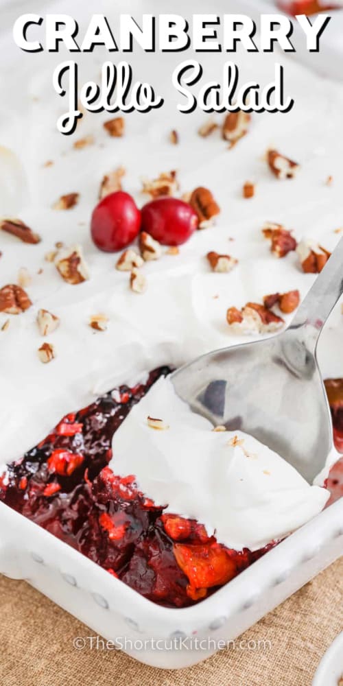 cranberry jello salad in a dish with a scoop being taken out and writing