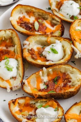 Loaded potato skins on a serving dish topped with sour cream and green onions