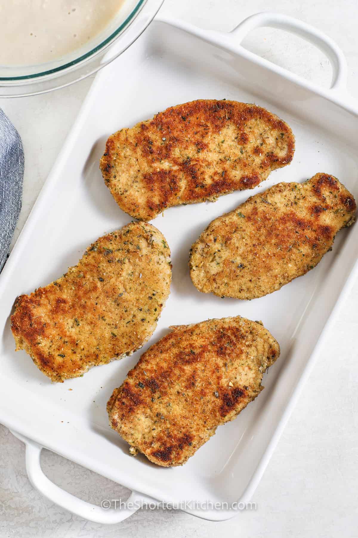 cooked pork chops in a dish to make Oven Baked Pork Chops